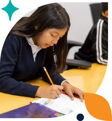 Girl in blue and white doing homework with pencil in a classroom