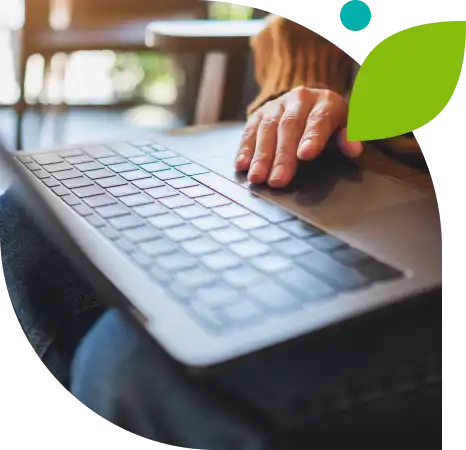 A hand near a laptop keyboard placed in the lap of the user